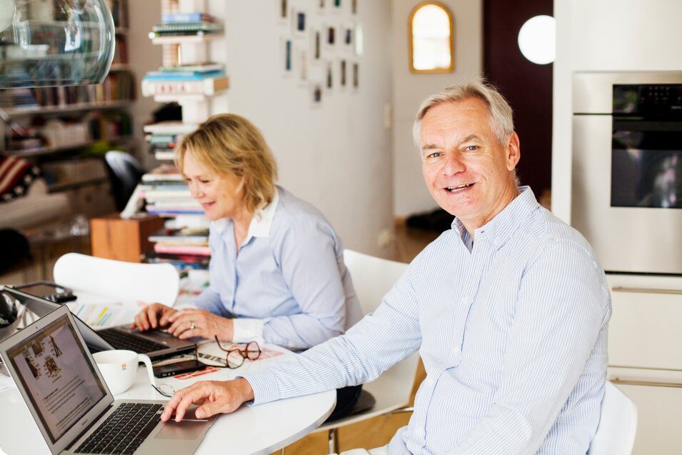 portrait of happy senior man with woman using laptop